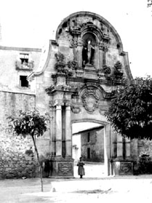 Una dona al peu de l'arc de Sant Benet davant del monestir. 1895-1905
