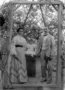 Retrat d'una parella i una criatura, dins la glorieta del jardí de la casa de la família Simon, a Tortellà. 1912-1913